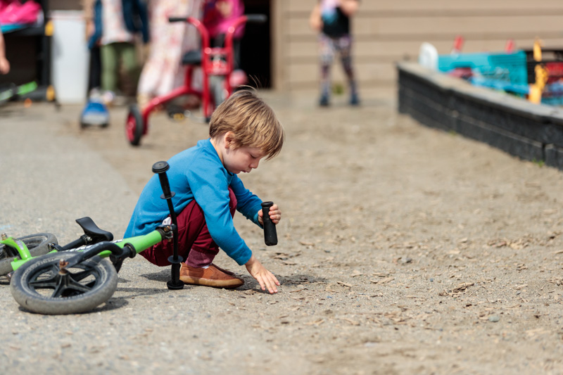 Millworks-2502-11 Boy playing with a toy crouching on sand